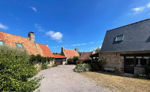 A courtyard with stone buildings, a gravel path, and a clear blue sky.
