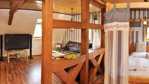 Un dormitorio con una cama con dosel, televisión, sofá y una mesa de comedor con fruta.