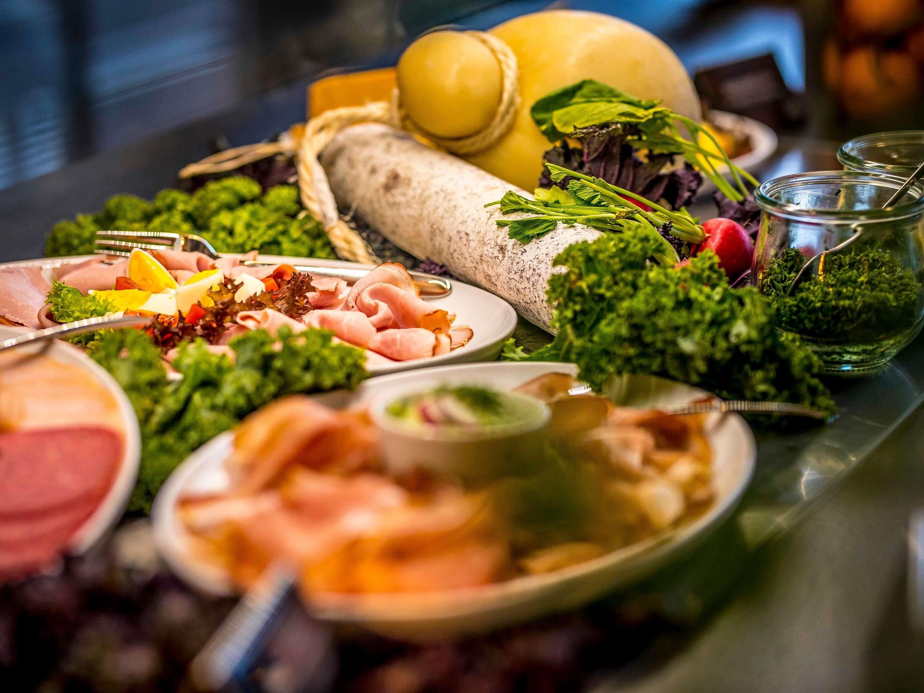 Een buffet met diverse gerechten, waaronder vlees, groenten en een gele meloen.