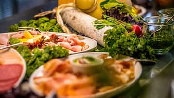 Een buffet met diverse gerechten, waaronder vlees, groenten en een gele meloen.