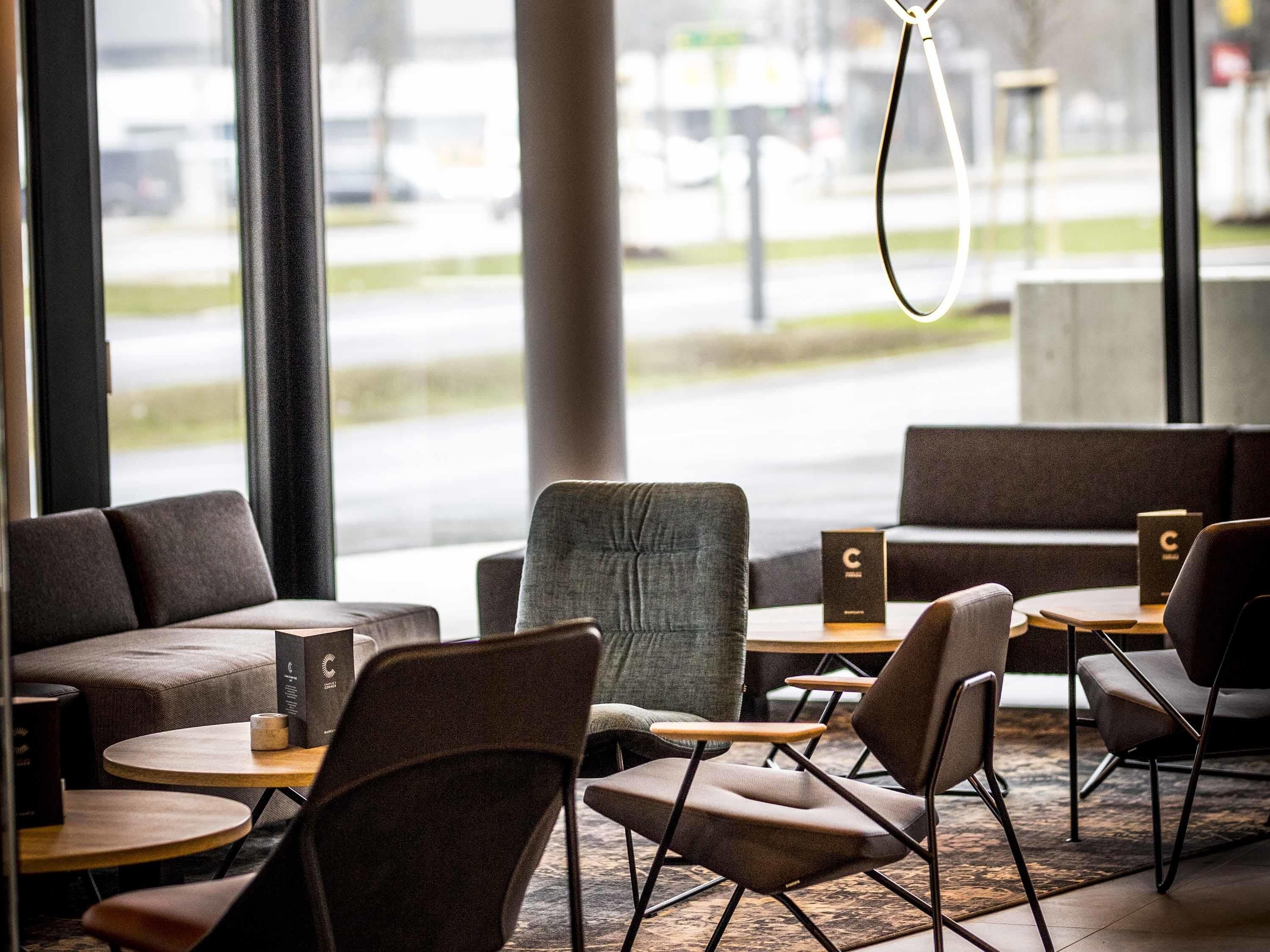 Interior de una cafetería moderna con mesas, sillas y vistas a la calle.