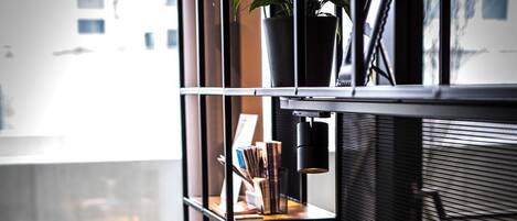 Un espacio de trabajo moderno con una computadora de escritorio, teclado, ratón y una silla negra. Hay una estantería con libros y una planta en maceta.