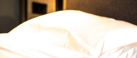 A hotel room with a bed, a wall clock, and a magazine on the bed.
