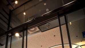 A modern interior with glass partitions, a reception desk, and a central light fixture. - Ibis Wels (Wels)