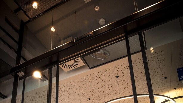 A modern interior with glass partitions, a reception desk, and a central light fixture. - Ibis Wels (Wels)