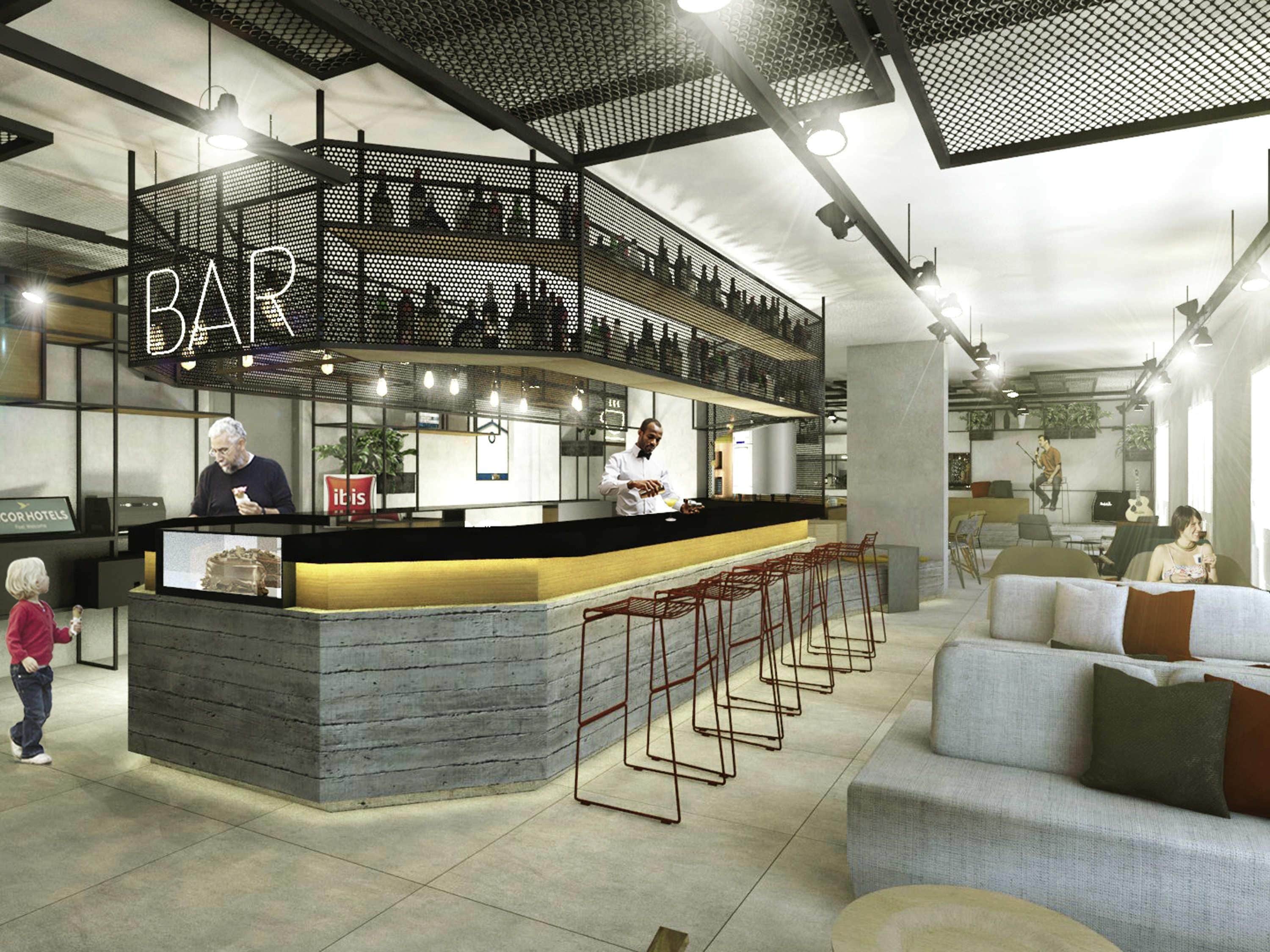 A modern bar area with a high ceiling, metal mesh design, and a counter with stools.
