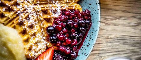 A plate with waffles, berries, and a strawberry.