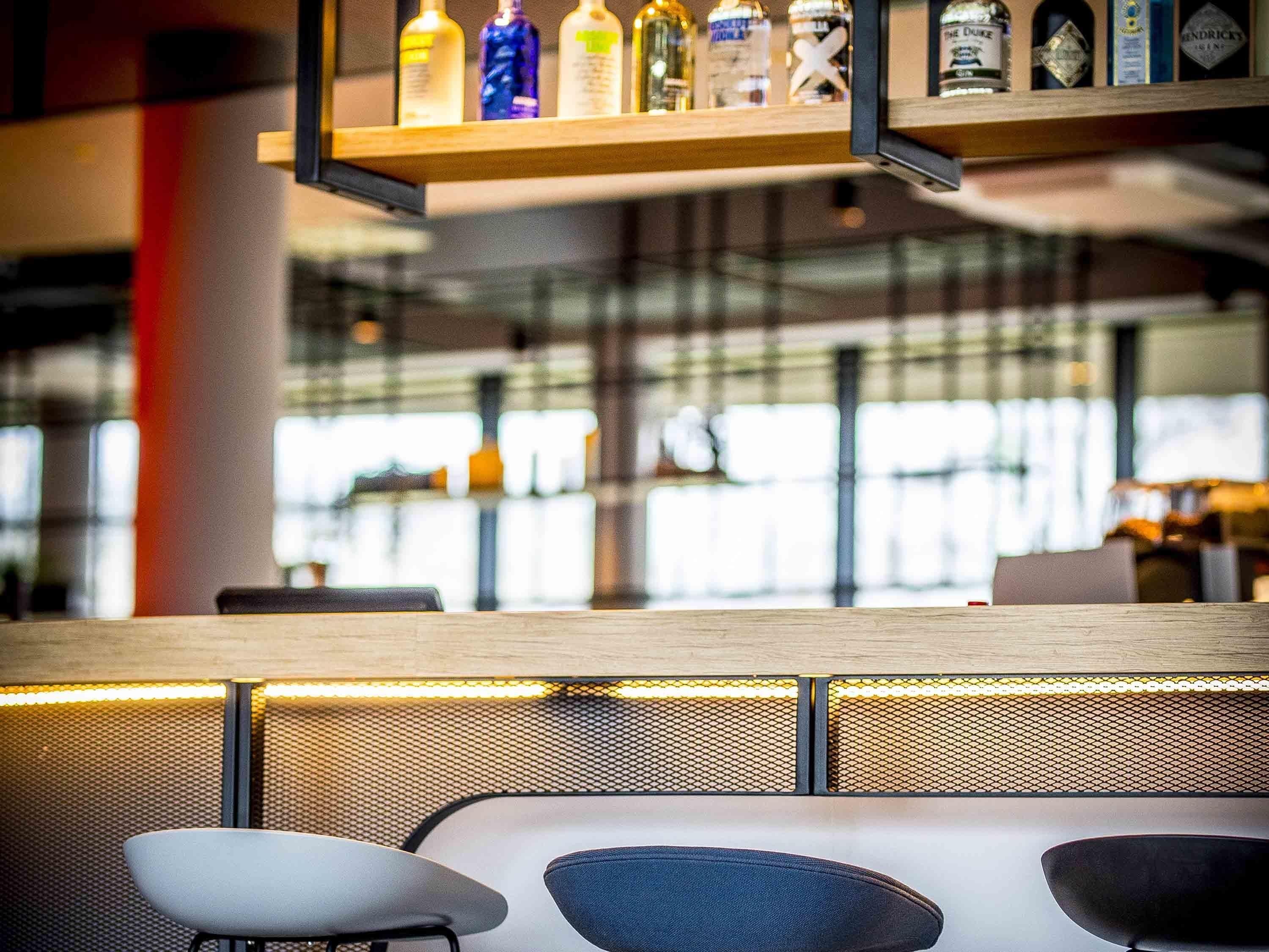 Un'area bar con scaffale di bottiglie di liquore, un salotto con poltrone imbottite e un design interno moderno.