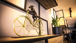 A room with a wooden desk, a potted plant, and a gold bicycle sculpture. - Ibis Wels (Wels)