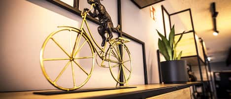 Una habitación con un escritorio de madera, una planta en maceta y una escultura de bicicleta dorada.