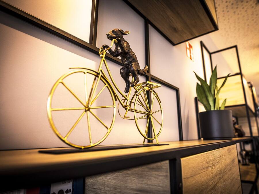 Ein Zimmer mit einem Holztisch, einem Blumentopf und einer goldenen Fahrradskulptur.