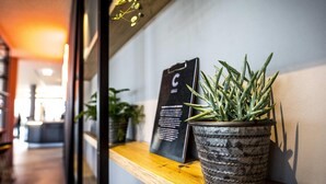 A potted plant on a shelf next to a black sign with white text. - Ibis Wels (Wels)