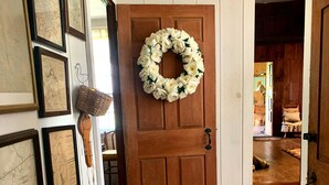 Una puerta de madera con un arreglo floral, un perro pequeño y cuadros en la pared.