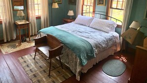 Un dormitorio con una cama de madera, una mesita de noche, una silla, una ventana con cortinas y una alfombra.