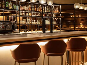 Een bar met flessen drank, glazen en een koffiemachine.