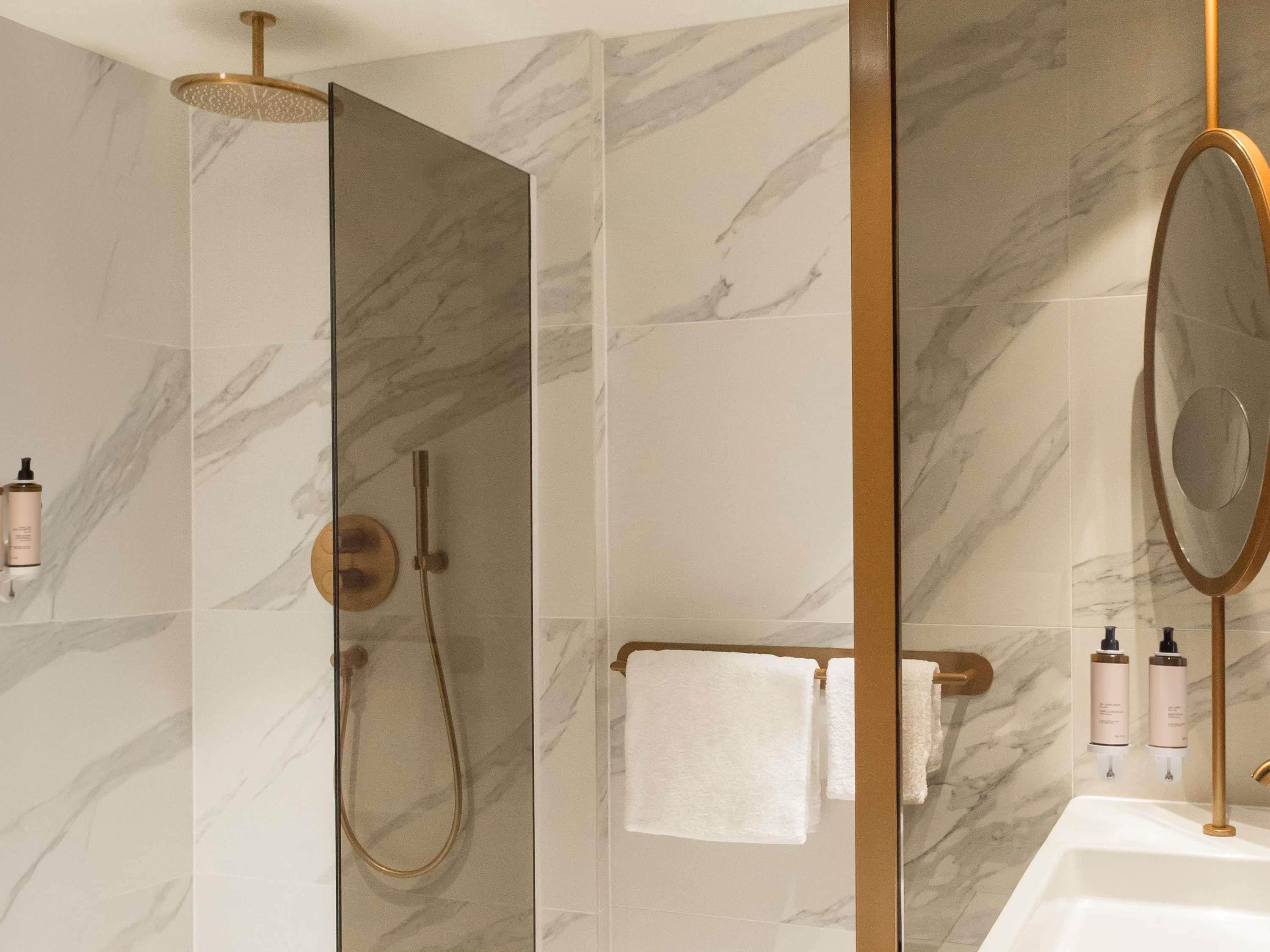 A bathroom with a shower, a mirror, and a sink.