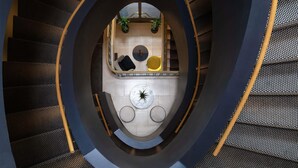 A spiral staircase with a central atrium featuring a seating area with round tables and chairs. - Mercure Luxembourg off Kirchberg (Luxembourg City)