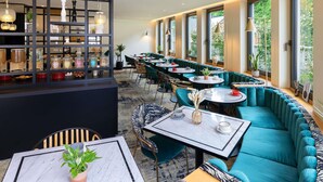 A modern restaurant interior with a bar area, seating arrangements, and large windows providing natural light. - Mercure Luxembourg off Kirchberg (Luxembourg City)