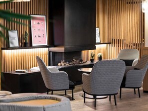 A modern interior with a fireplace, patterned chairs, and framed artwork on the wall. - Mercure Luxembourg off Kirchberg (Luxembourg City)