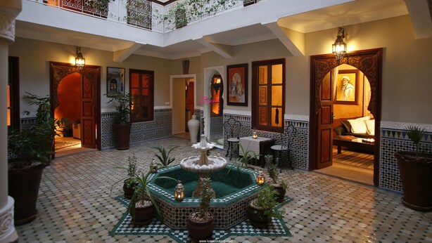 A spacious courtyard with a central fountain, surrounded by potted plants and a tiled floor. - Riad Teranga (Marrakech)