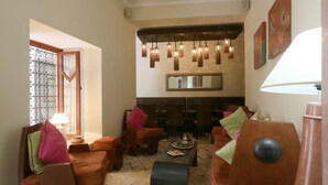 A cozy lounge area with wooden furniture, a central coffee table, and hanging pendant lights. - Riad Teranga (Marrakech)