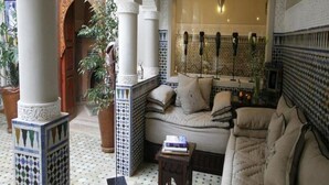 A cozy lounge area with a sofa, a small table, and decorative columns. - Riad Teranga (Marrakech)