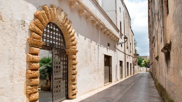 A narrow street with a stone archway and a metal gate. - La corte dei mille (Presicce-Acquarica)