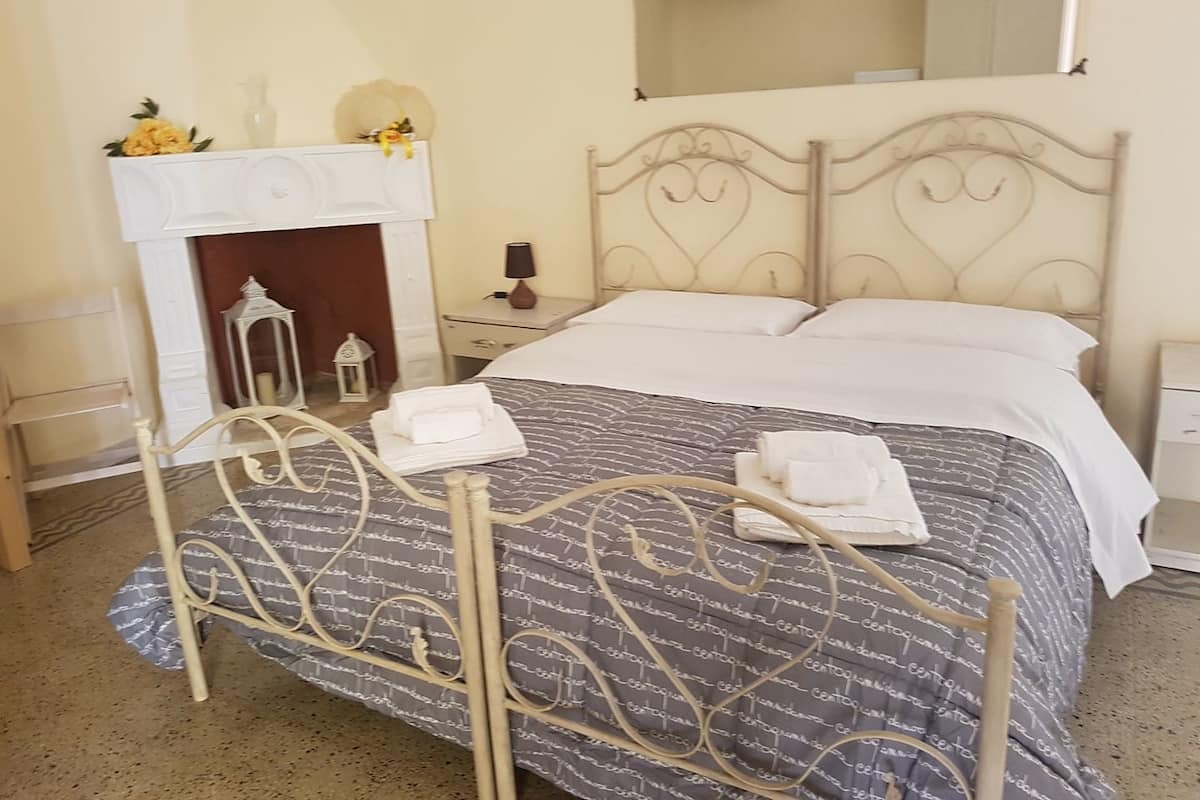 Ein Schlafzimmer mit Bett, Nachttisch, Spiegel und Kamin.