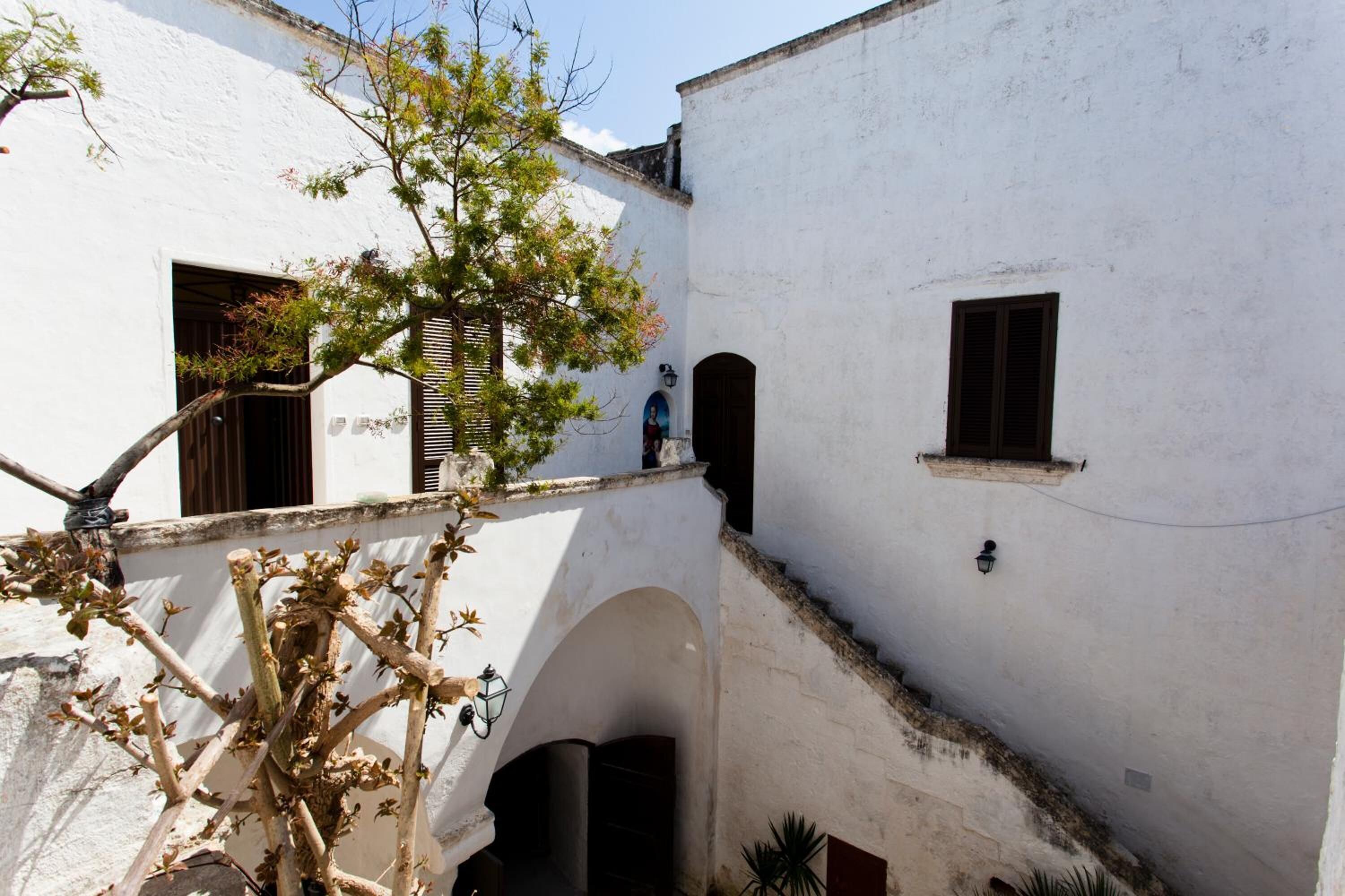 Un bâtiment blanc doté d’un petit balcon, d’une fenêtre et d’une arche.