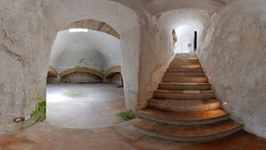 A spiral staircase in a stone-walled interior with arched doorways and a tiled floor. - La corte dei mille (Presicce-Acquarica)
