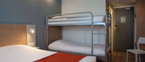 Een slaapkamer met een stapelbed, een enkel bed, een stoel en een deur.