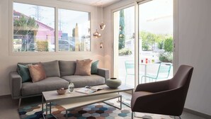 Ein modernes Wohnzimmer mit einer Couch, einem Couchtisch und Sesseln, große Fenster mit Blick nach draußen.