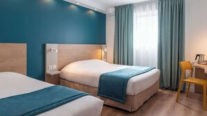 Ein Hotelzimmer mit zwei Betten, einem Schreibtisch und einem Sessel.
