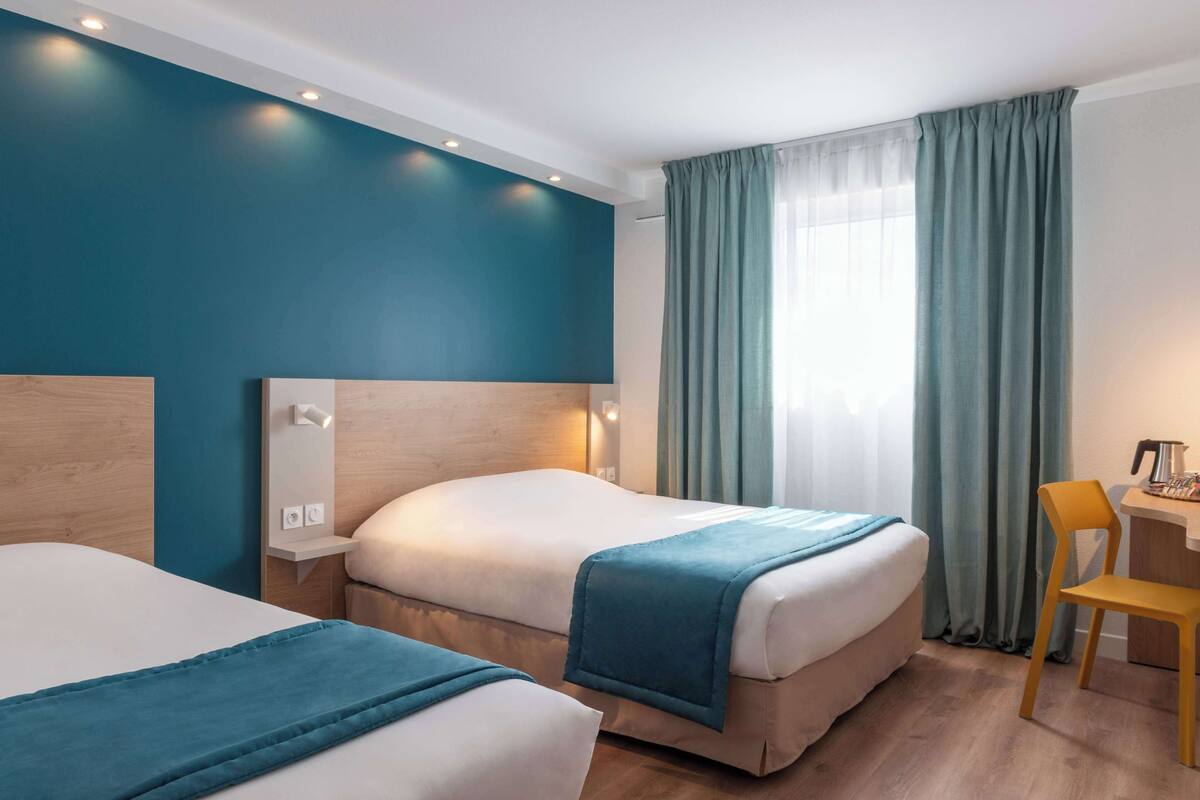 Une chambre d’hôtel avec deux lits, un bureau et une chaise.