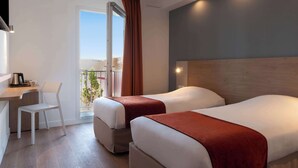 Ein Hotelzimmer mit zwei Betten, einem Schreibtisch mit Stuhl und einem Balkon mit Blick.