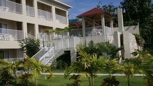 Um hotel com vários andares, varandas, área de estar coberta ao ar livre e paisagismo exuberante.
