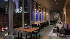 Un espace bar moderne doté de hauts plafonds, de grandes fenêtres et d’une variété de sièges, notamment des tables et des chaises.