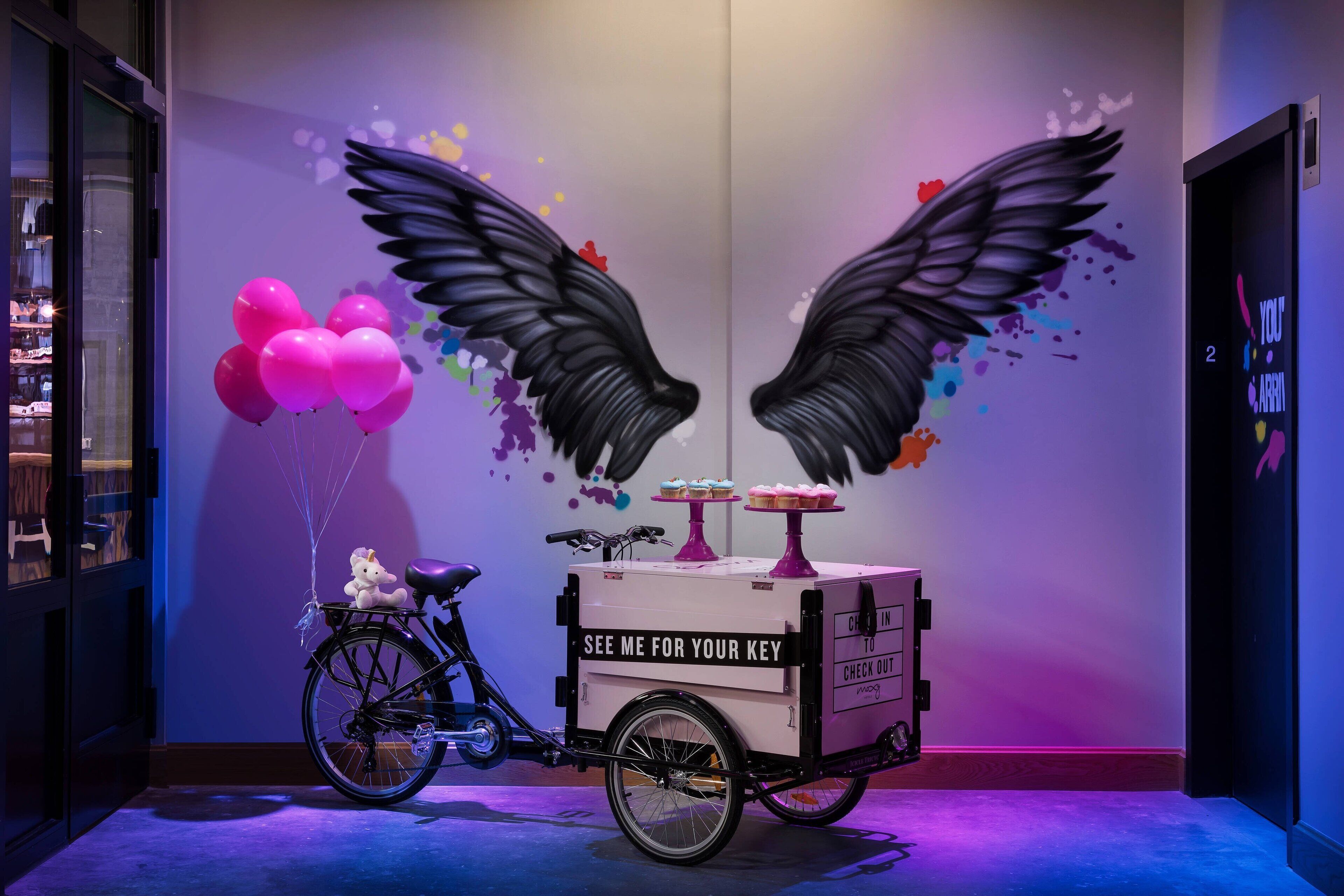 A bicycle with a cart labeled 'SEE ME FOR YOUR KEY' and balloons.