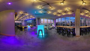 Un espace bar moderne, doté d’un aménagement incurvé, de nombreux types de sièges et de grandes fenêtres offrant une vue sur la ville.