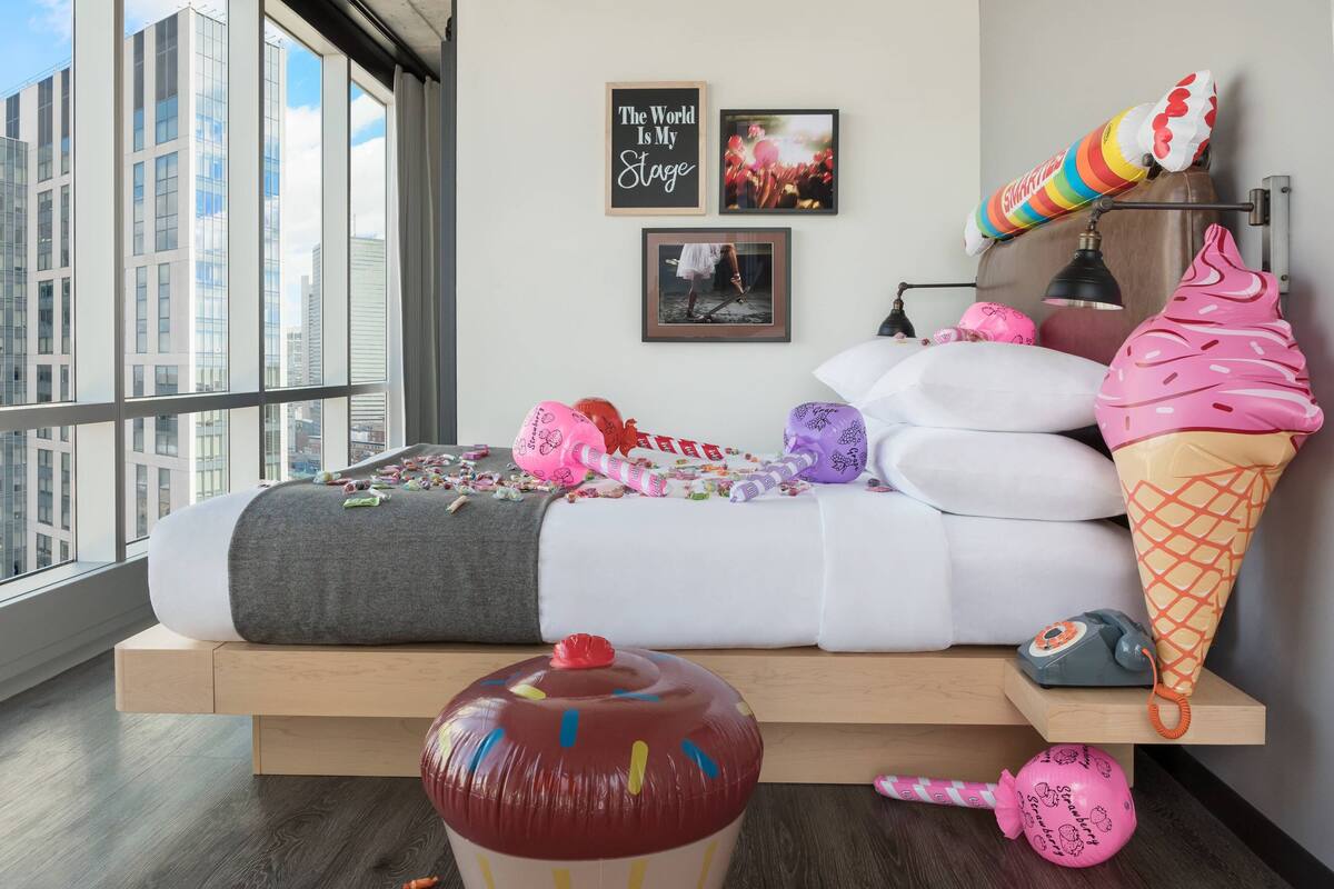 A modern bedroom with a bed, pillows, and a large window.