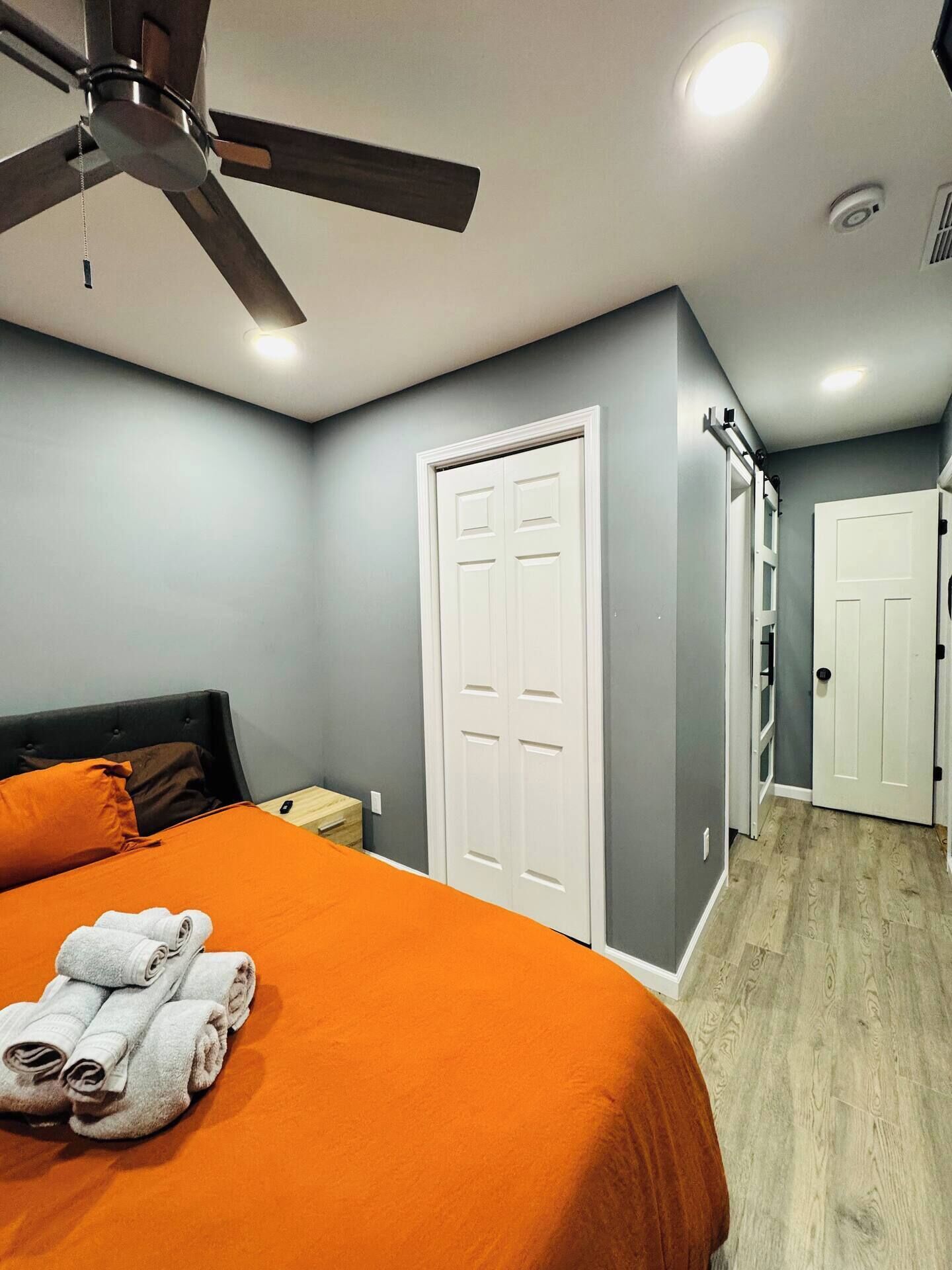 A bedroom with a bed, a ceiling fan, and a white door.