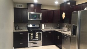 Una cocina moderna con armarios oscuros, electrodomésticos de acero inoxidable y encimera de granito.