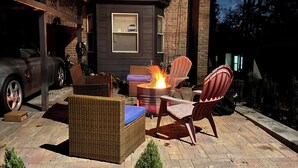 Un patio al aire libre con mobiliario de mimbre, una chimenea y plantas en macetas.