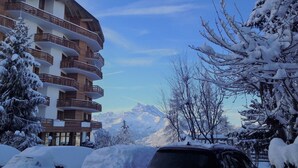A multi-story building with balconies, surrounded by snow-covered trees and mountains in the background. - Villars Bristol Apartments (Ollon)