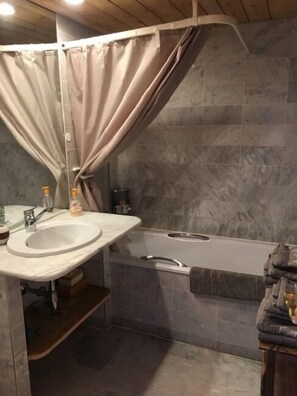 A bathroom with a sink, mirror, and bathtub.