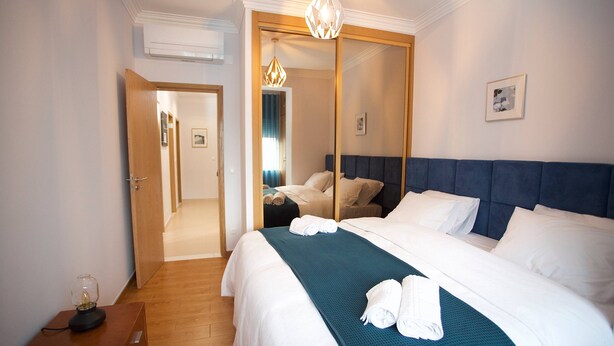 A hotel room with a large bed, a mirror, a wooden nightstand, and a chandelier. - Meriteluna Sky Sintra (Sintra)