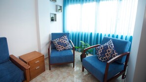 A living room with two blue armchairs, a wooden side table, and a potted plant. - Meriteluna Sky Sintra (Sintra)