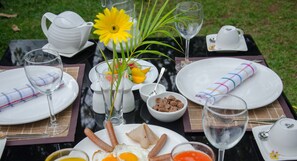 A table set for a meal with plates, glasses, and a flower centerpiece. - Visu Villa (Habarana)