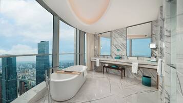 Un baño moderno con bañera, suelo de mármol, tocador con espejo y vistas a la ciudad.