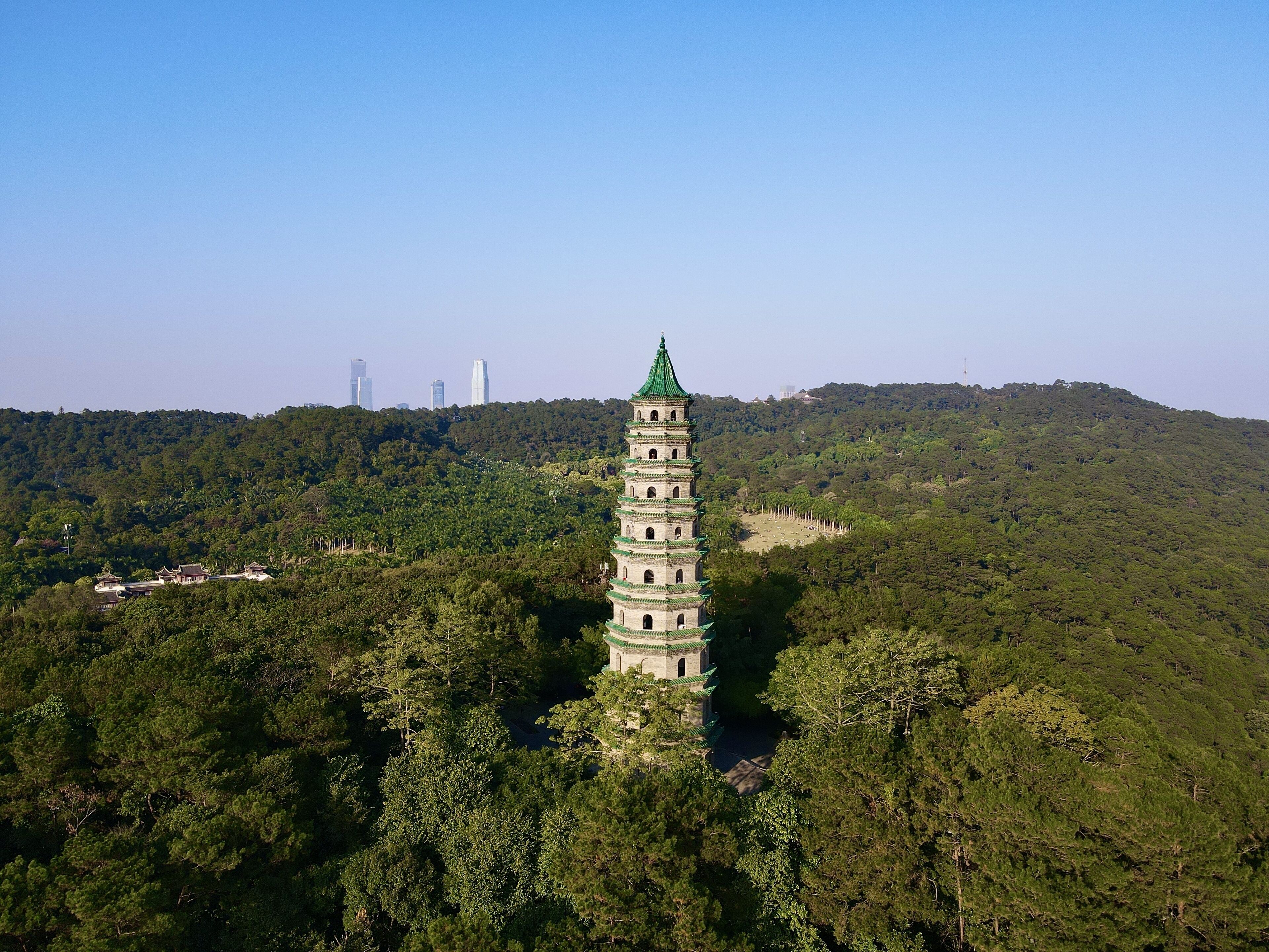 Una pagoda con tetto verde, circondata da una fitta foresta e dolci colline.